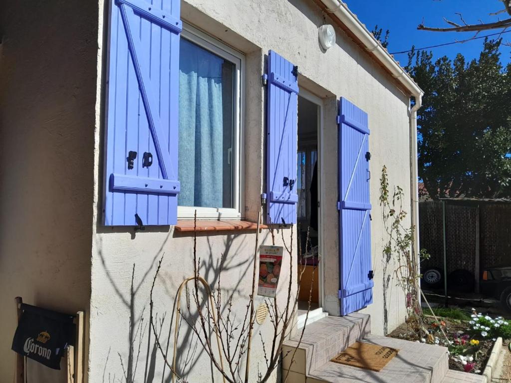 une maison avec des volets bleus sur les fenêtres dans l'établissement Petite Maison au barcares 4 personnes, au Barcarès