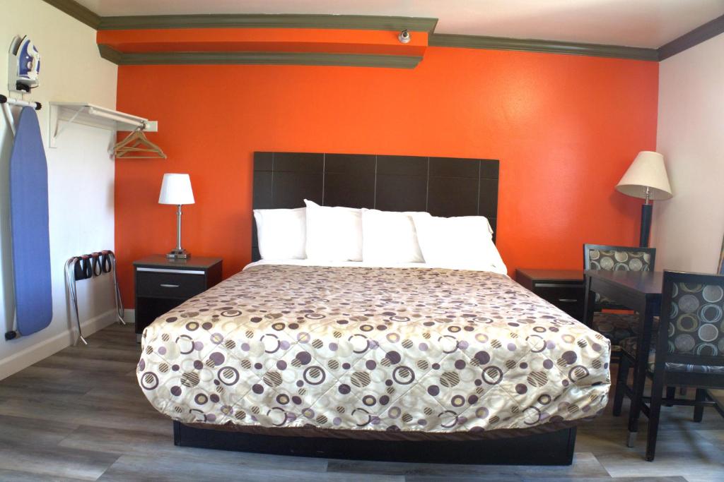 Un dormitorio con una cama con una pared naranja. en Lambert Inn, en Whittier
