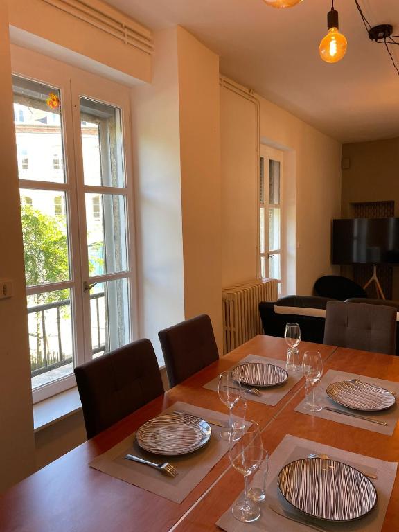une salle à manger avec une table avec des assiettes et des verres à vin dans l'établissement Triplex - Au cœur de Fougères, à Fougères