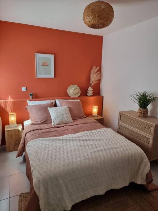 une chambre avec un grand lit avec un mur orange dans l'établissement Maison cosy aux portes de Tours, à Saint-Pierre-des-Corps