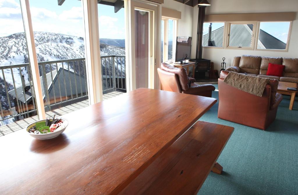 uma sala de estar com uma mesa de madeira em frente às janelas em Timbertop em Mount Hotham