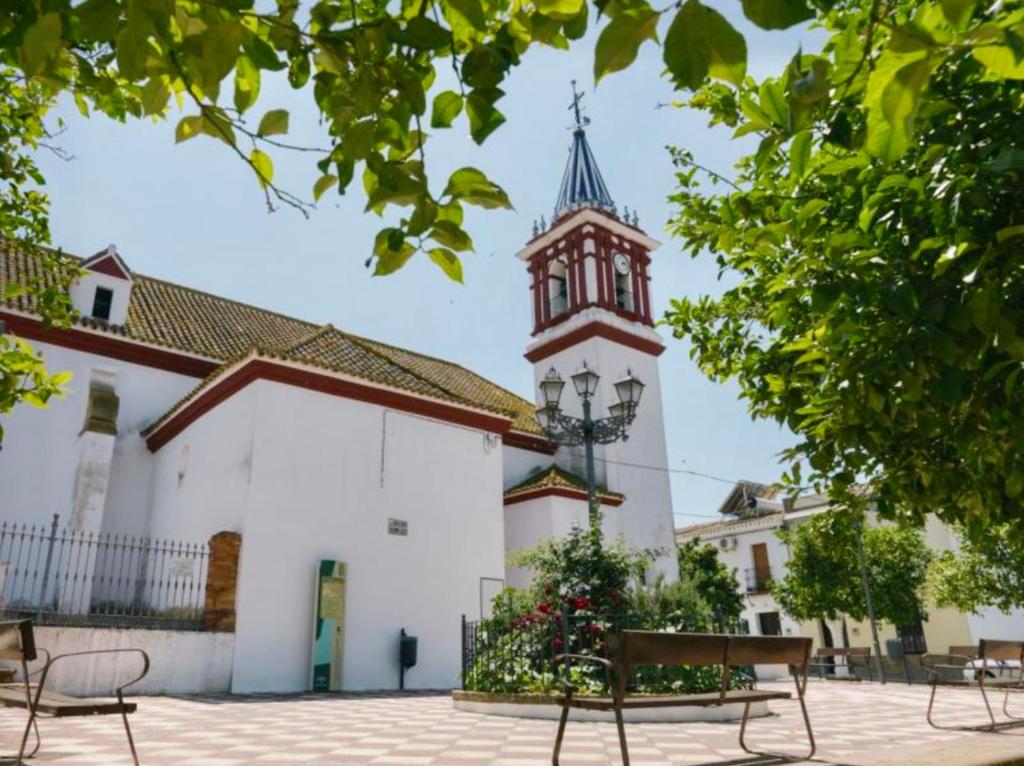 a building with a clock tower and a bench at Casa Rural Familiar , Castilleja del Campo , Sevilla in Seville