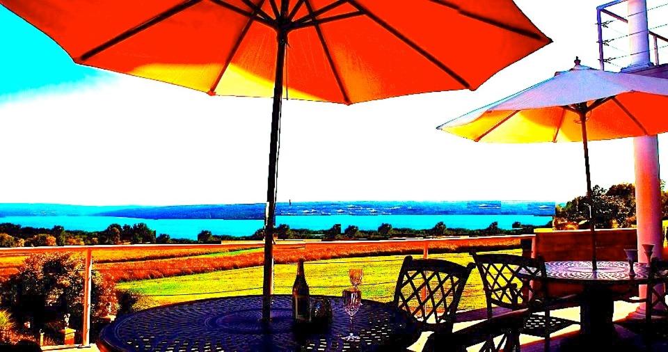 a table with two umbrellas on a patio with a view at A Cayuga LakeFront Inn - Hotel Alt, Ithaca New York in Ithaca