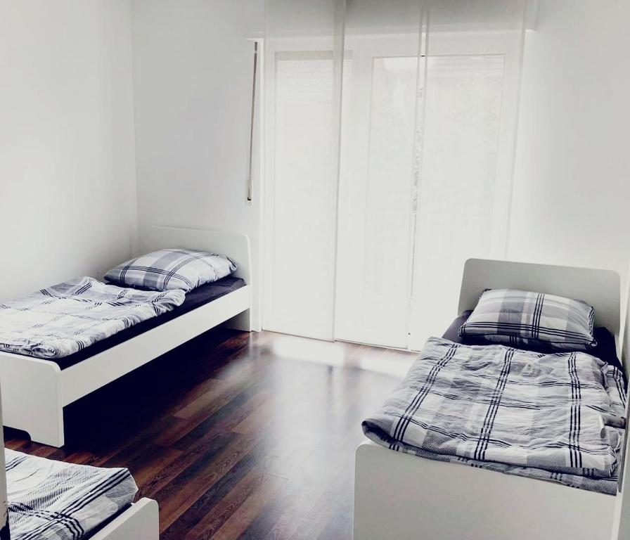 two beds in a room with white walls and wood floors at 2 Zimmer Unterkunft zentrumsnah in Bocholt