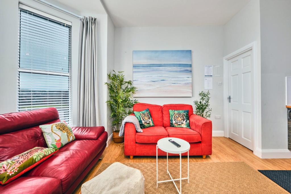 a living room with a red couch and a table at West Beach 3 - Portrush by the Sea in Portrush