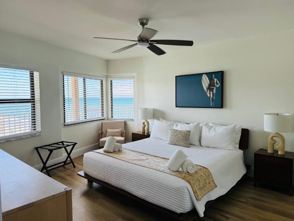 a bedroom with a large white bed with a ceiling fan at Melbourne Beach Resort & Surf Club in Melbourne Beach