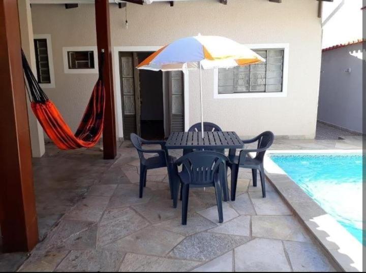 einen Tisch und Stühle mit einem Sonnenschirm neben einem Pool in der Unterkunft Aurora dos Pireneus in Pirenópolis