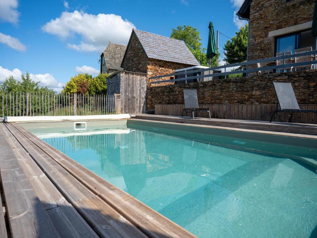 a large swimming pool with a wooden bench in front of a house at Gite Les Corbieres in Grand-Vabre