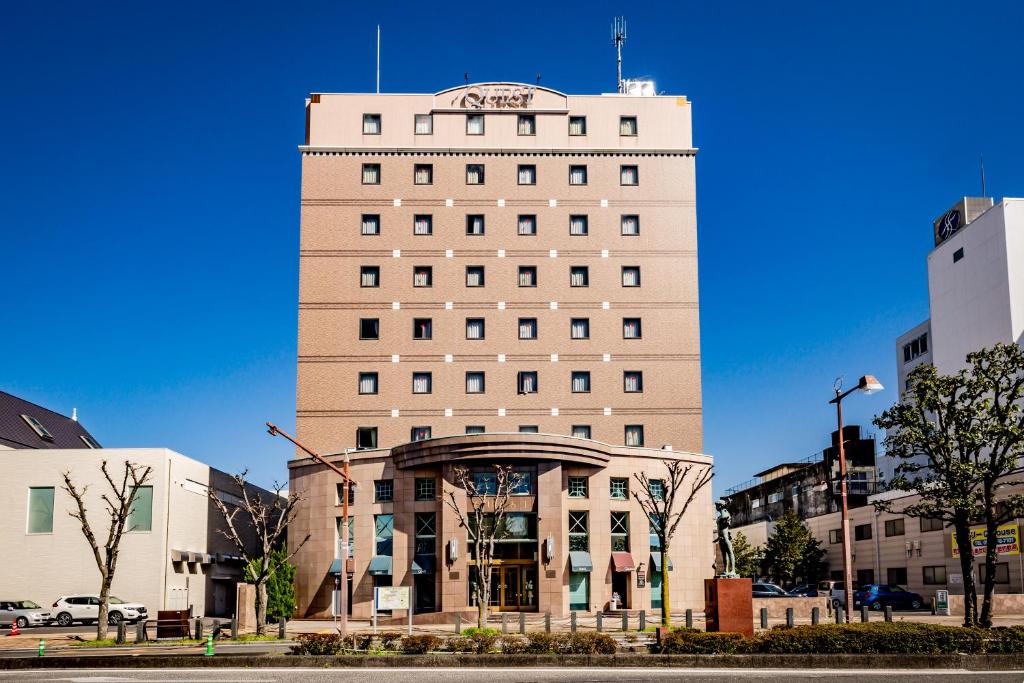 a tall white building with a sign on top of it at Hotel Quest Shimizu in Shizuoka