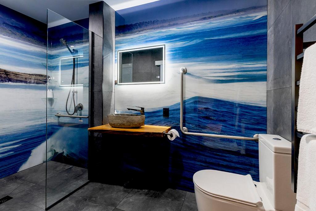 a bathroom with a mural of the ocean on the wall at Punakaiki Treehouse Limited in Punakaiki