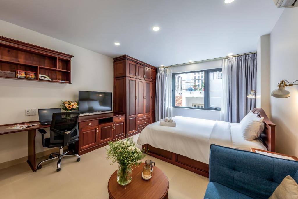 a bedroom with a bed and a desk and a tv at Woody House Saigon Center in Ho Chi Minh City