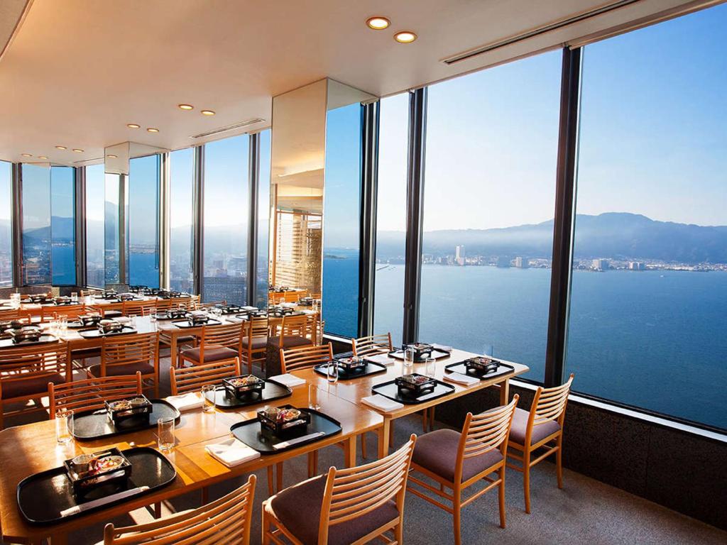 a restaurant with tables and chairs and a view of the water at Lake Biwa Otsu Prince Hotel in Otsu