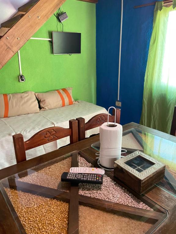 Una habitación con una mesa y una cama y una mesa de cristal con un control remoto. en Cabañas La Felicidad, en Merlo