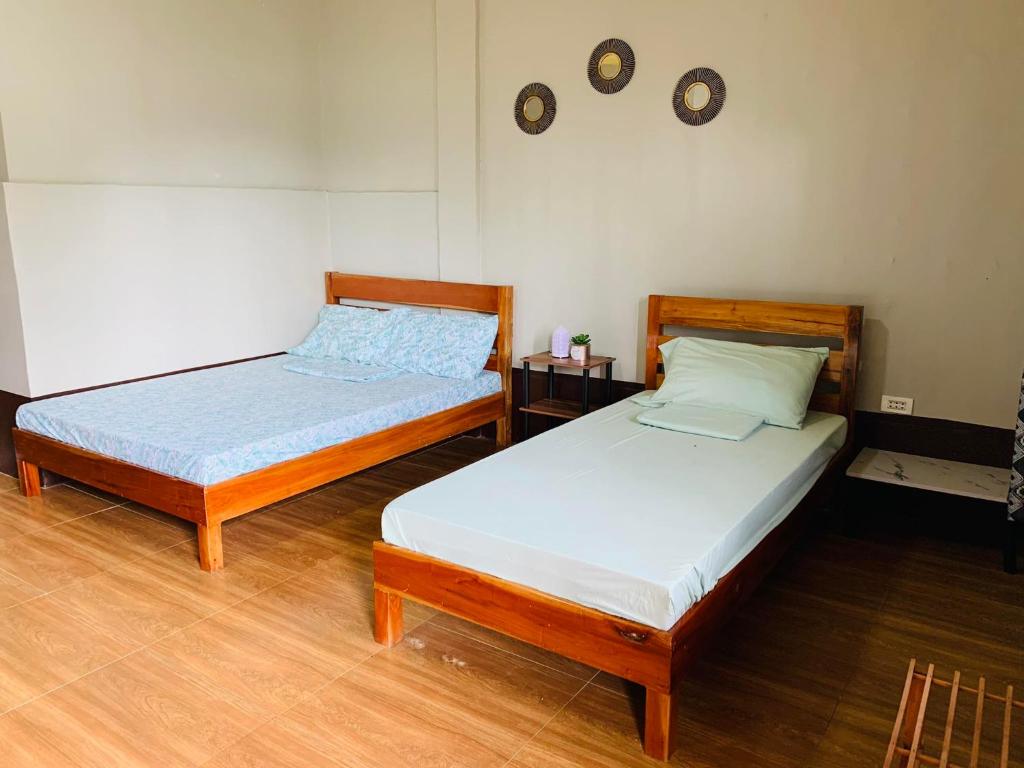 two twin beds in a room with wooden floors at Emelita affordable bed and breakfast in Dauis