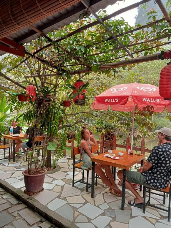 twee mannen aan een tafel onder een paraplu bij Hoalu Ecolodge Homestay in Ninh Binh