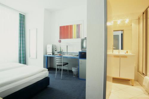 a room with a bed and a desk and a kitchen at Hotel Alt - Tegel in Berlin