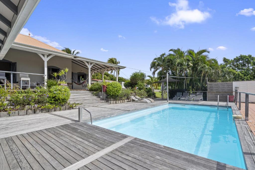 a swimming pool with a deck and a house at Villa Belle Etoile in Le Vauclin