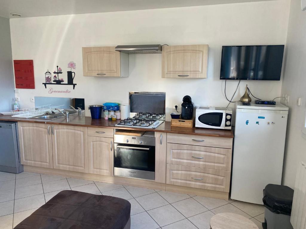 une cuisine avec des armoires en bois et un réfrigérateur blanc dans l'établissement Gîte de la chapelle, à Landrethun-lès-Ardres