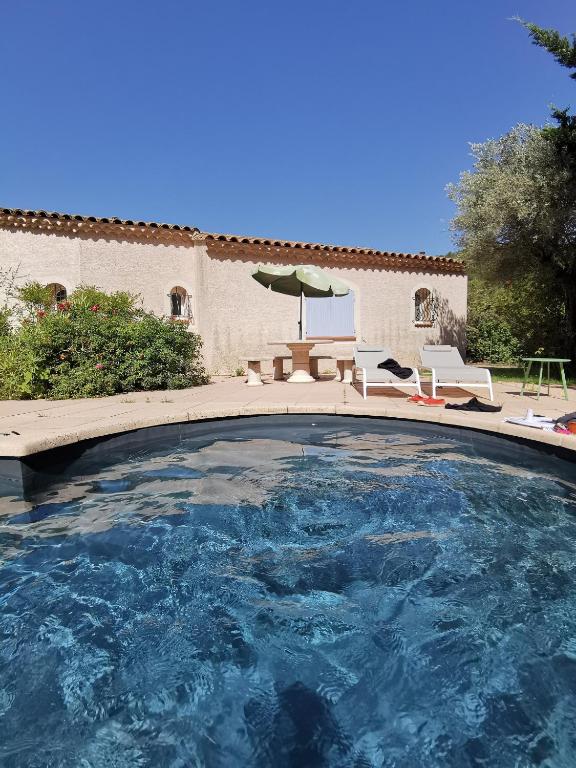 une grande piscine avec des chaises et un parasol dans l'établissement Le Loriot, à Auriol