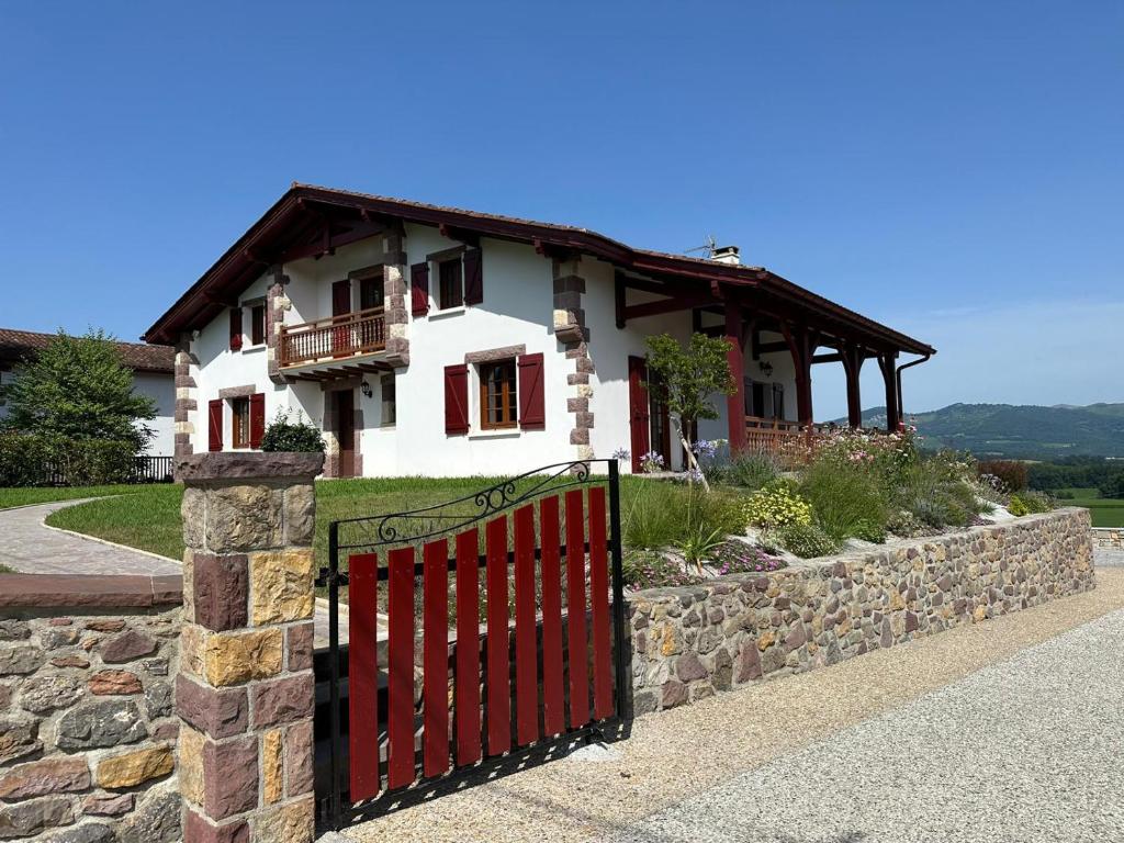a house with a red gate and a stone wall at Location d'une maison typique du Pays Basque in Caro