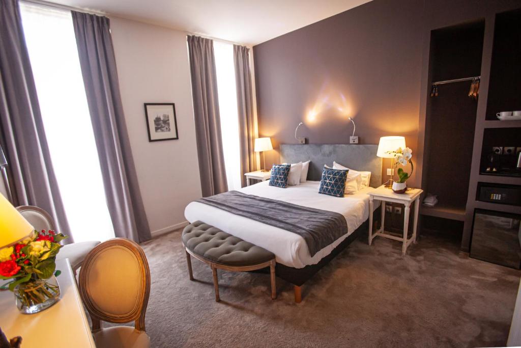 a hotel room with a bed and a desk at Hôtel Churchill Bordeaux Centre in Bordeaux