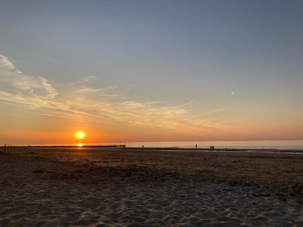 a sunset on a beach with the sun setting at Huis van Marietje in Aardenburg