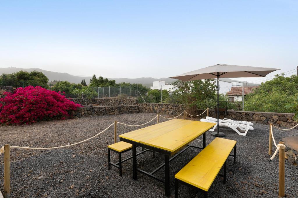 a picnic table with two benches and an umbrella at La Casa Amarilla in El Paso