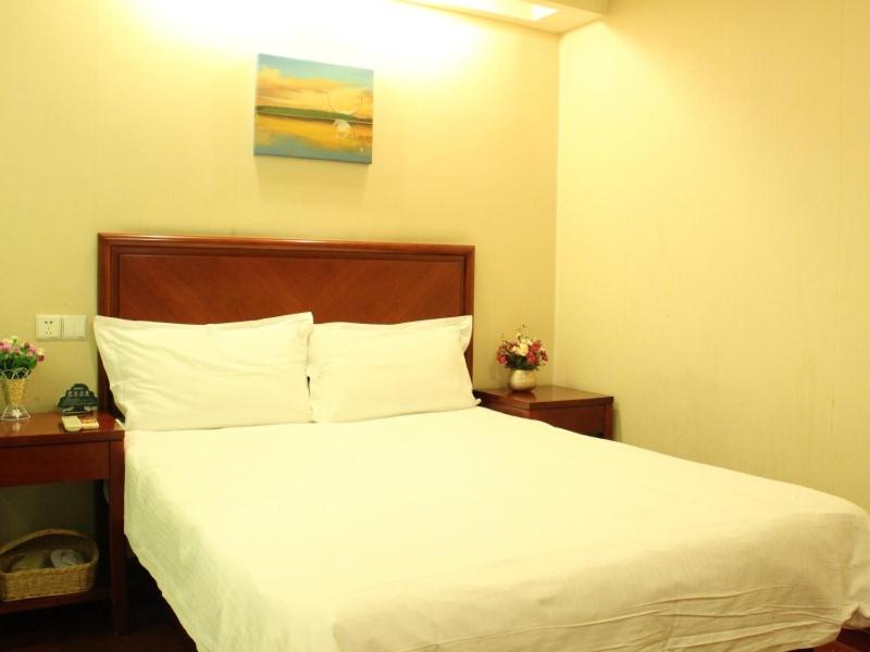 1 dormitorio con 1 cama con sábanas blancas y 2 mesas en GreenTree Inn Shandong Qingdao Jiaozhou Datong Mansion Express Hotel en Jiaozhou