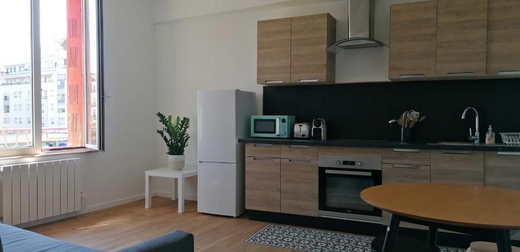 une cuisine avec une table et un réfrigérateur blanc dans l'établissement Appartement F2 coeur de Vichy bellle vue, à Vichy