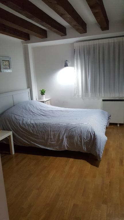 a bedroom with a white bed and a wooden floor at Edificio con 2 opciones DUPLEX 3 DORMITORIOS Y APARTAMENTO 1 DORMITORIO EN PLAZA MAYOR in Segovia