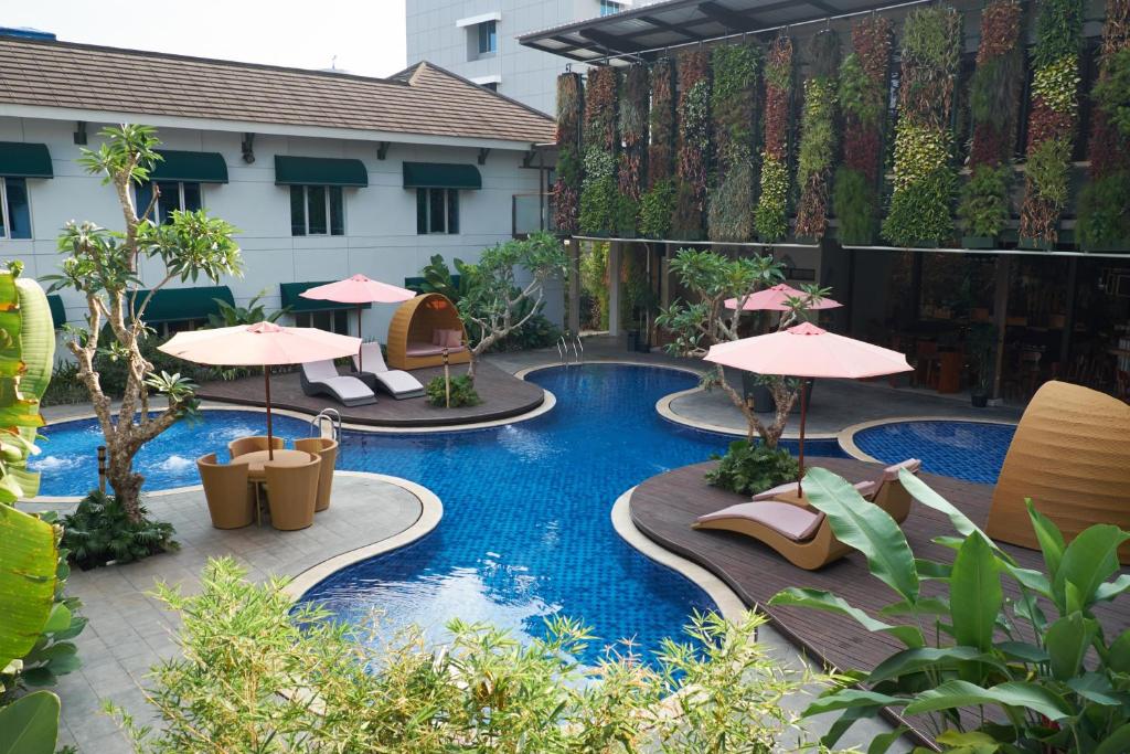 a pool with chairs and umbrellas in a courtyard at Patra Bandung Hotel in Bandung