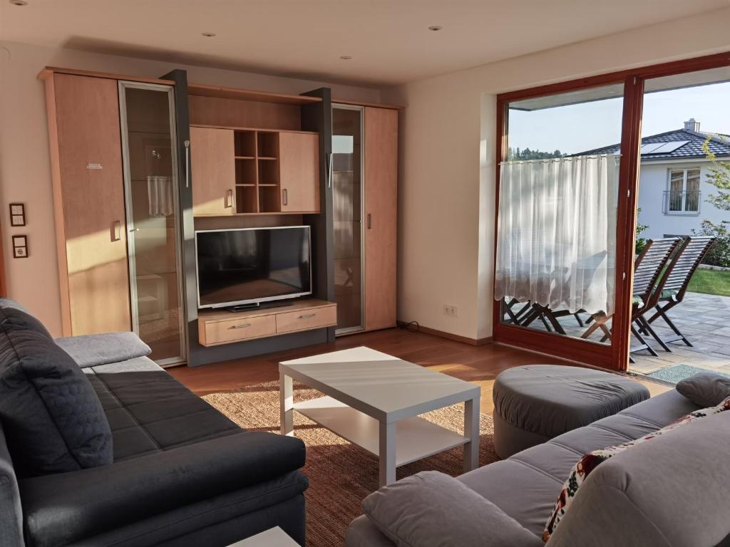 un soggiorno con un divano, una TV e un tavolo di Ferienwohnung Im Himmelreich, 83 qm, ruhig gelegen, optimal für Familien, Küche, Waschmaschine und Trockner a Deggendorf