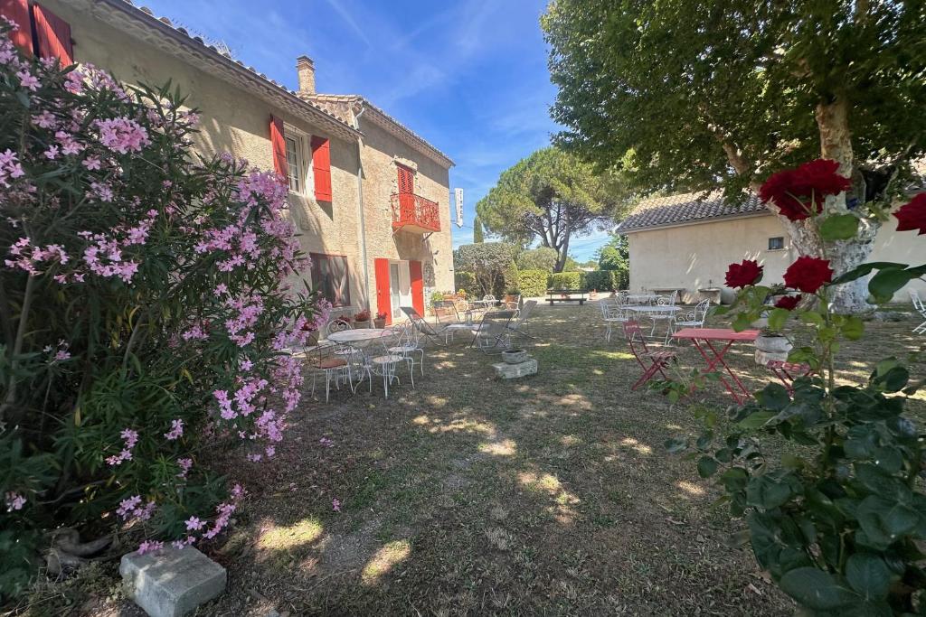 un jardin avec des fleurs et des tables ainsi qu'un bâtiment dans l'établissement La Maison de Constance - Charmante Maison provençale 3 chambres, à Aigues-Mortes