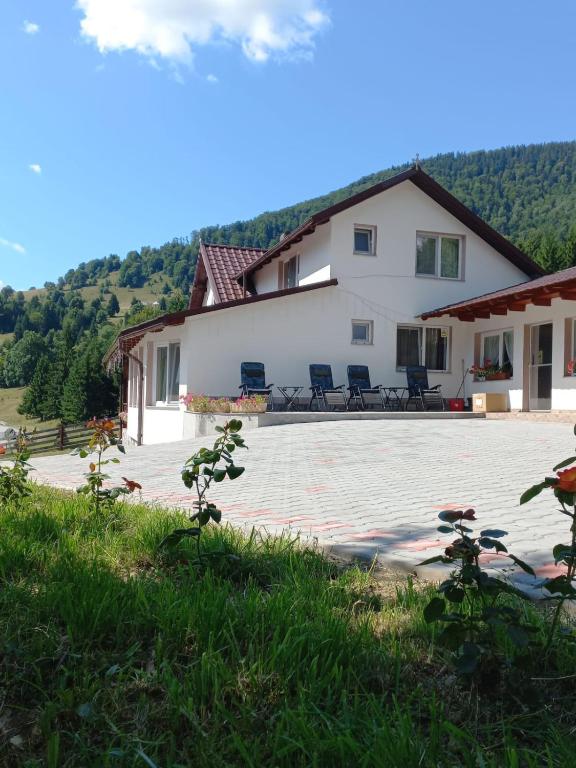 a large white house with chairs in front of it at Cabana Forest in Piatra Fantanele