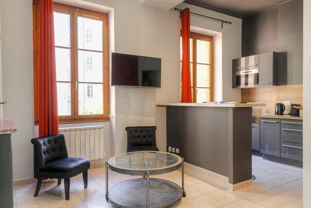 une cuisine avec une table en verre et deux chaises dans l'établissement Studio charmant idéalement situé, Ainay-Carnot, à Lyon