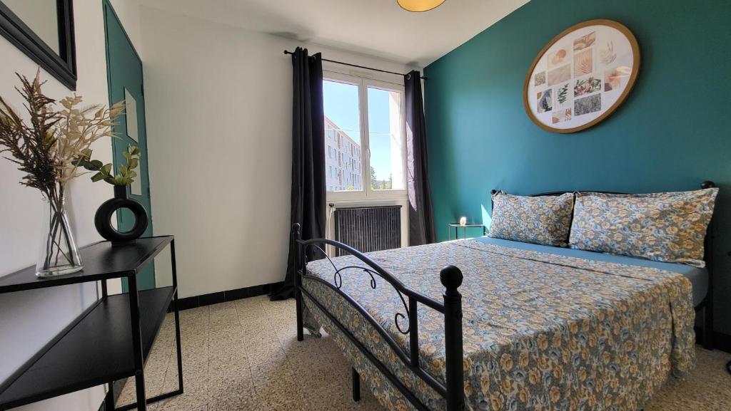 une chambre avec un lit aux murs bleus et une fenêtre dans l'établissement Les Tourterelles d'Avignon 2, à Avignon