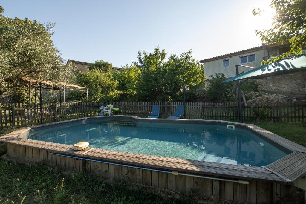a pool in a yard with chairs and an umbrella at Les Oliviers - Le Chant des Tongs in Salazac