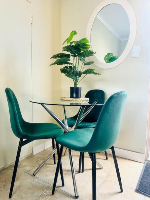a table with four green chairs and a mirror at Greens Haven, Your Private escape in Cape Town in Cape Town