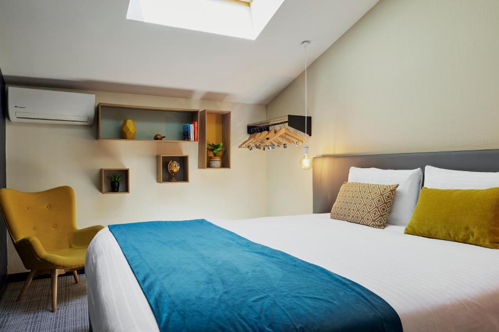 a bedroom with a large bed and a chair at Hotel Nap By HappyCulture in Nice