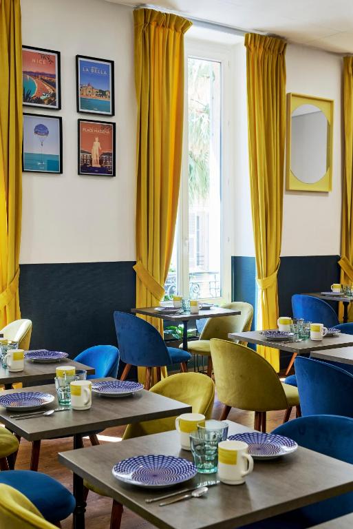 a restaurant with tables and chairs with yellow curtains at Hotel Nap By HappyCulture in Nice