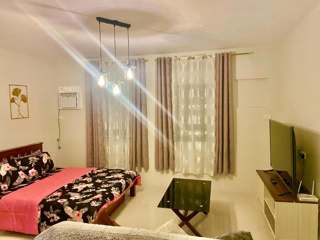 Un dormitorio con una cama y un televisor y una ventana. en spacious condo unit 1P olvera residences, en Bacolod