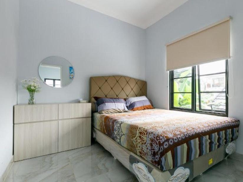 a bedroom with a large bed and a mirror at Stylish Villa at Green Apple U 35A Cipanas Puncak in Sindanglaya