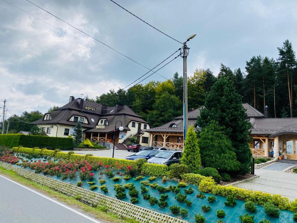 a house with a garden with flowers in the street at Hotel i Gospoda Pod Kamieniem in Lipnica Murowana