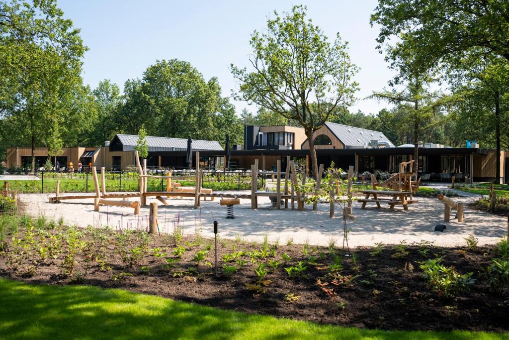 einen Spielplatz in einem Park mit einem Gebäude im Hintergrund in der Unterkunft Resort de Brabantse Kempen in Lage Mierde