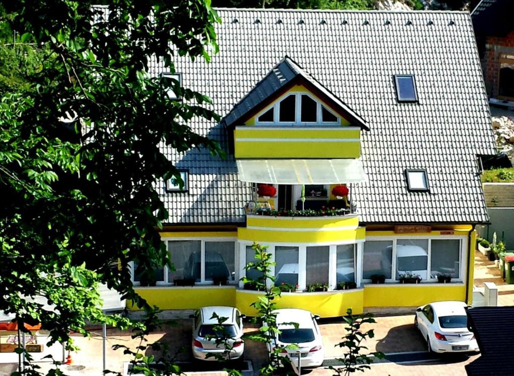 a yellow house with cars parked in front of it at Apartments Violeta in Bled