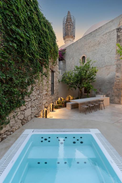 a swimming pool in a courtyard with a stone wall at Lemon Garden Villa in Rethymno
