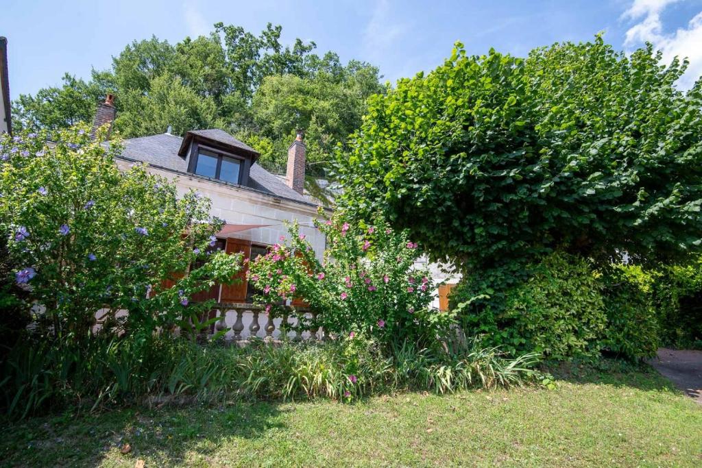 ein altes Haus mit einem Zaun und einigen Büschen in der Unterkunft La petite maison sur la colline in Nazelles
