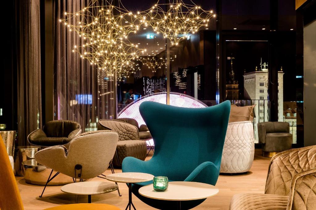 Una habitación con sillas y mesas y una lámpara de araña. en Motel One Leipzig-Post, en Leipzig