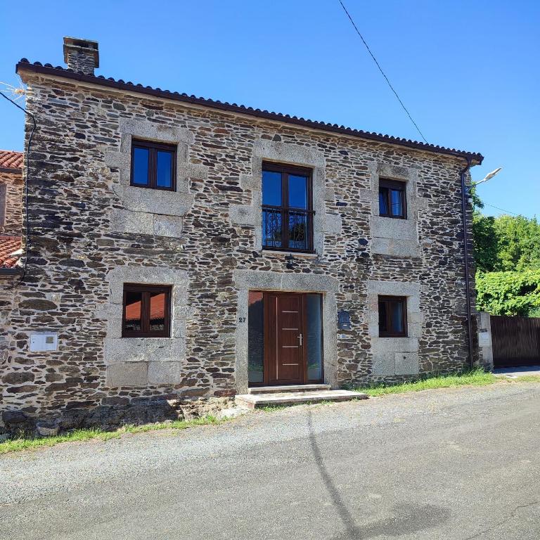 a stone building with a brown door and windows at O Lar da Crega in O Pino 