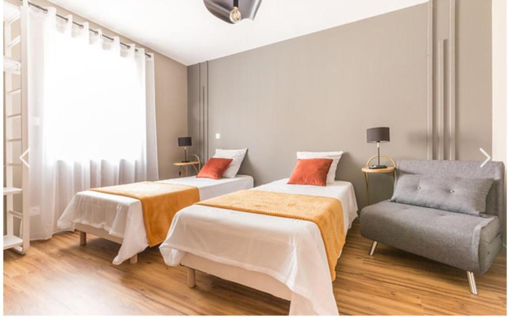 une chambre avec deux lits et une chaise dans l'établissement Appartement Modulable, à Arras